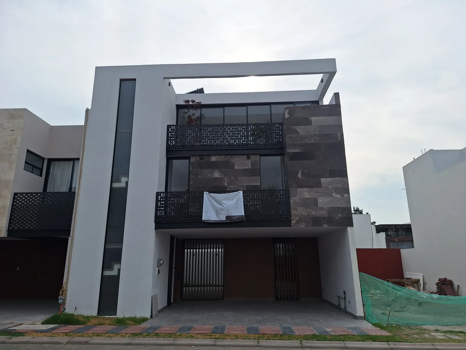 Fachada de tres niveles con piedra oscura y herrería — casa Missouri 99 en el corredor Angelópolis, Puebla